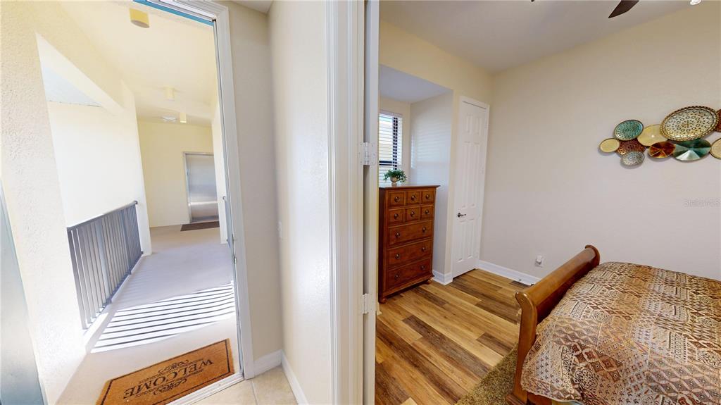 A bedroom with wood-look flooring is visible through a doorway next to a hallway — 1340 ROCK DOVE COURT UNIT 143, PUNTA GORDA, FL