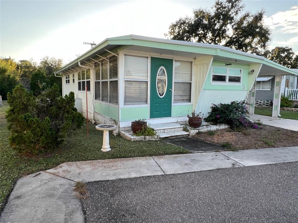 A light green mobile home features a teal front door and a covered carport — 29250 US HIGHWAY 19 N UNIT 301, CLEARWATER, FL