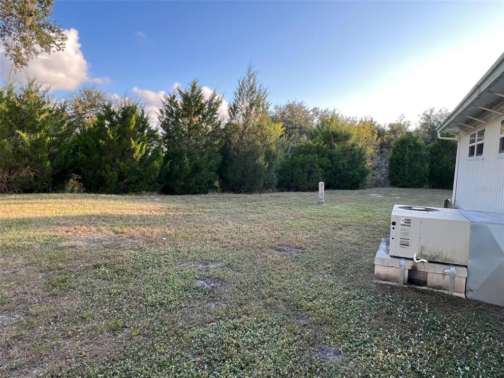 A grassy backyard features a central utility post and an outdoor HVAC unit near a house — 29250 US HIGHWAY 19 N UNIT 301, CLEARWATER, FL
