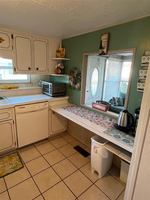 A kitchen features white cabinets, a dishwasher, a pass-through window, and tiled flooring — 29250 US HIGHWAY 19 N UNIT 301, CLEARWATER, FL