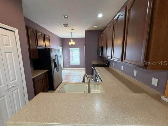 A kitchen features brown cabinets, a stainless steel refrigerator, and a beige countertop with sink — 9118 SABAL PINE WAY, ORLANDO, FL