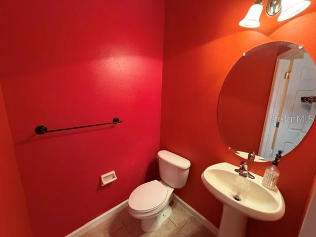 A small bathroom features bright red walls, a white pedestal sink, and a white toilet — 9118 SABAL PINE WAY, ORLANDO, FL