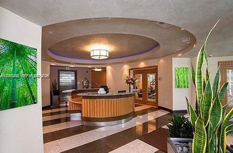 A curved reception desk sits in a lobby with a circular ceiling feature and tile floors — MIAMI, FL