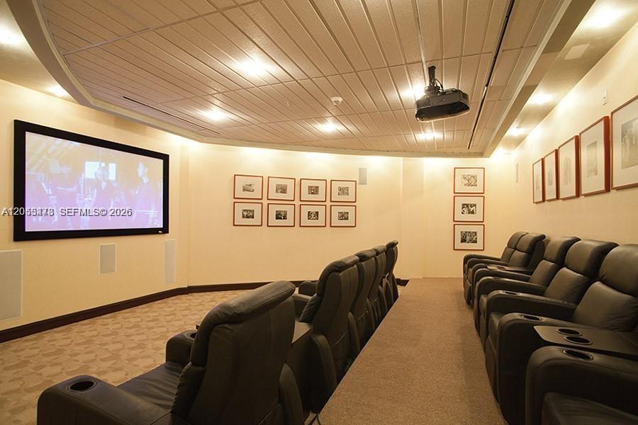A home theater room features rows of leather recliners, a large projection screen, and recessed lighting — MIAMI, FL