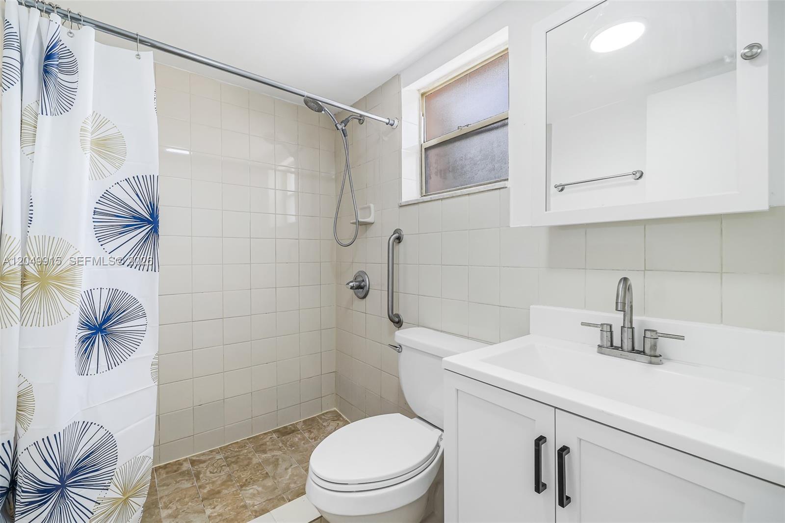 A bathroom features a tiled shower, a white vanity, and a toilet with a grab bar — 6200 W Flagler St # 208, Miami FL 33144, MIAMI, FL