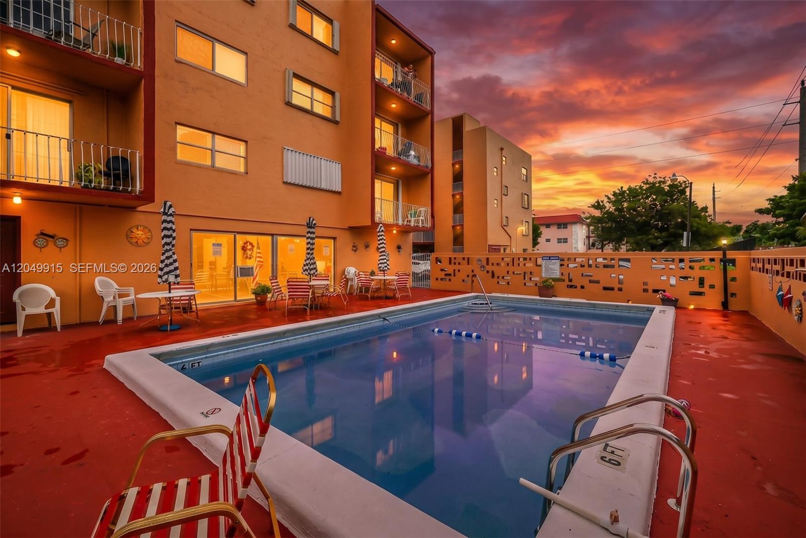 A rectangular swimming pool sits on a red patio beside a multi-story apartment building — 6200 W Flagler St # 208, Miami FL 33144, MIAMI, FL