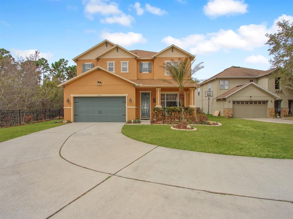 A two-story, tan-colored suburban house with a two-car garage and a concrete driveway — 15214 GALBI DRIVE, ORLANDO, FL