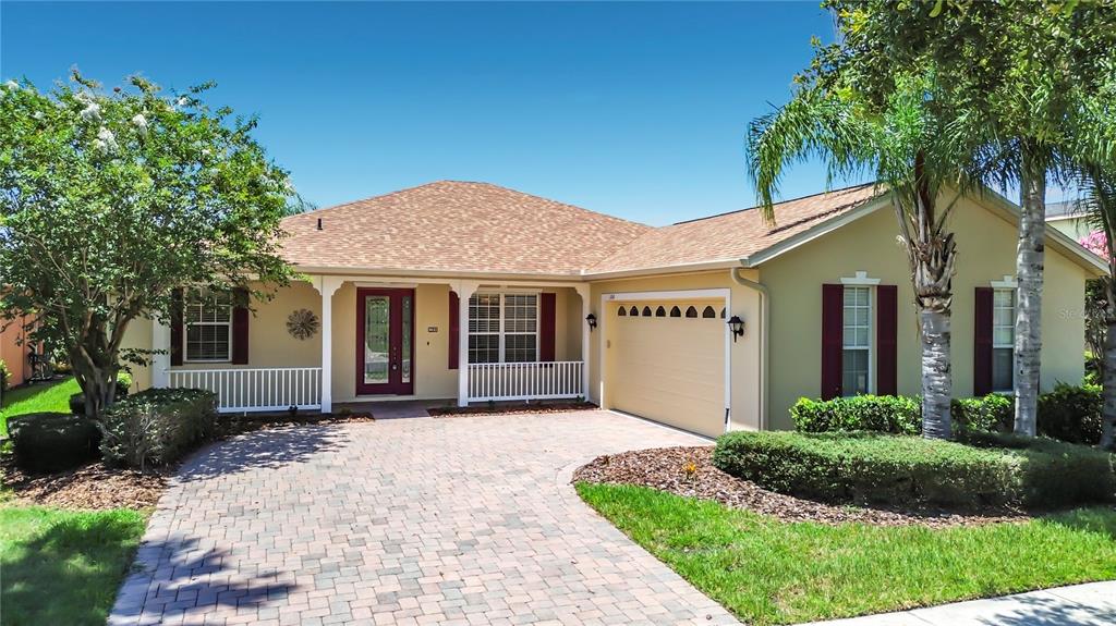 A single-story house with a tan exterior, red shutters, a brick driveway, and a garage — 106 PRIMA DRIVE, POINCIANA, FL