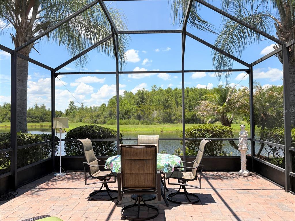 A screened-in patio features a dining set overlooking a pond and wooded area — 106 PRIMA DRIVE, POINCIANA, FL