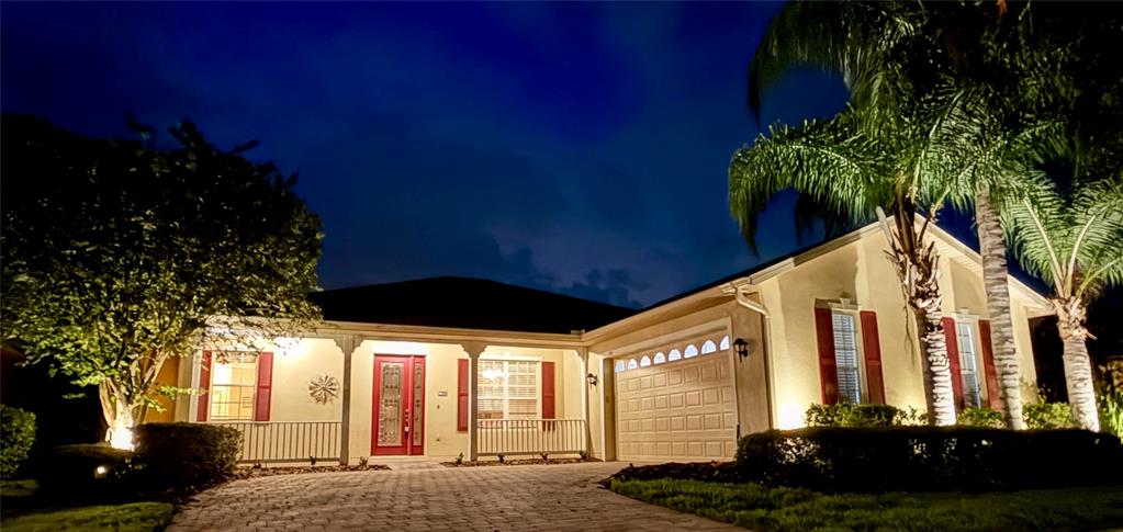 A single-story house with a red front door and garage at night — 106 PRIMA DRIVE, POINCIANA, FL
