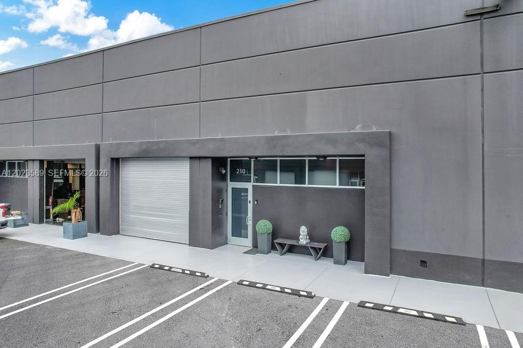 The exterior of a commercial building features a gray facade, a roll-up door, and an entrance — 6030 NW 102nd Ave # 210, Doral FL 33178, DORAL, FL
