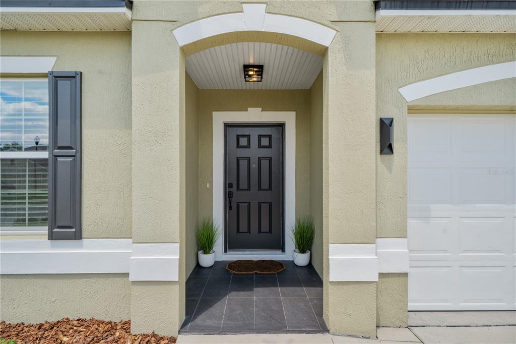 The exterior view shows a front entryway with a black door, tiled porch, and garage — 880 NW 251ST DRIVE, NEWBERRY, FL
