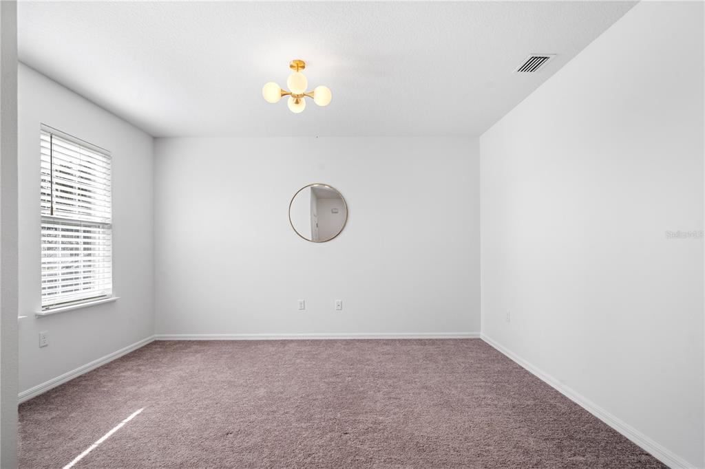 An empty room with white walls, brown carpet, a window with blinds, and a light fixture — 880 NW 251ST DRIVE, NEWBERRY, FL