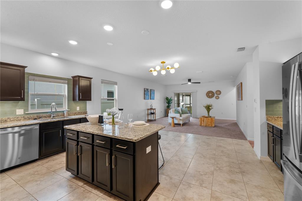 A kitchen with dark cabinets and granite countertops opens into a carpeted living area — 880 NW 251ST DRIVE, NEWBERRY, FL