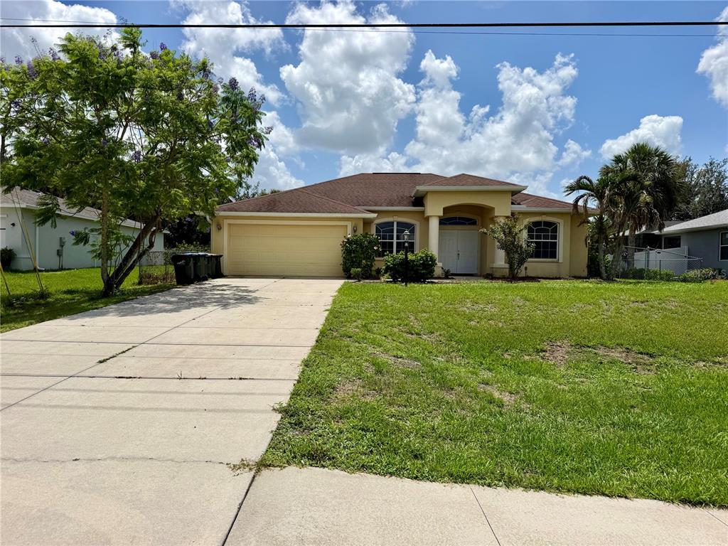 A single-story yellow stucco house with a two-car garage and a concrete driveway — 1204 S SAN MATEO DRIVE, NORTH PORT, FL