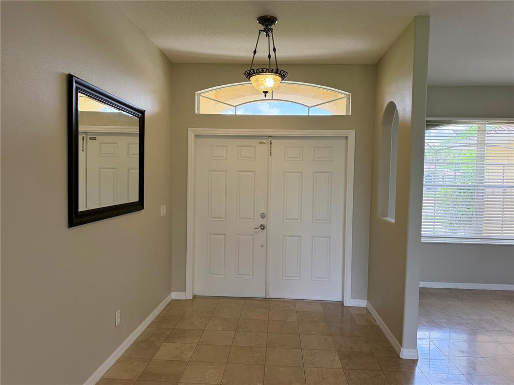 An entryway features double doors, a transom window, a hanging light fixture, and tile flooring — 1204 S SAN MATEO DRIVE, NORTH PORT, FL