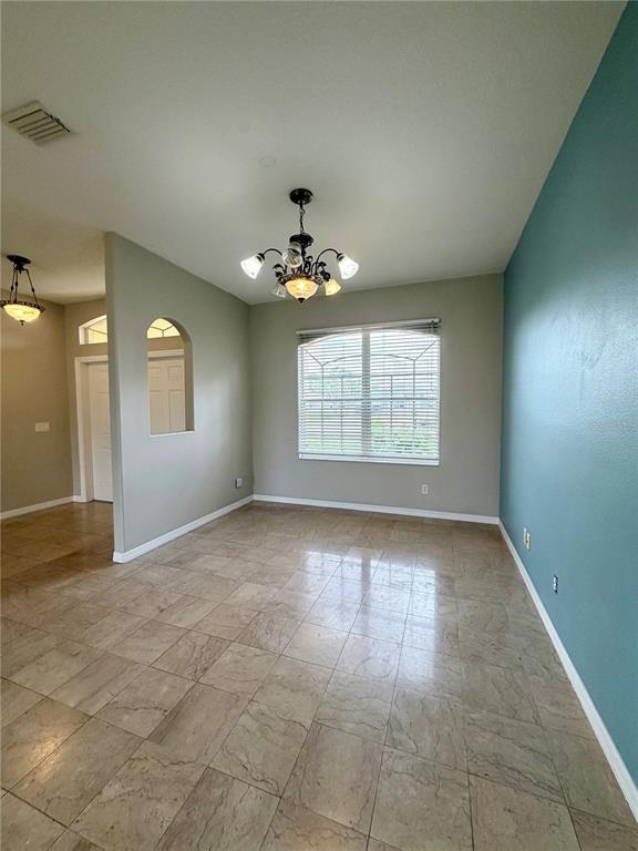 A dining room features tile flooring, a chandelier, and a blue accent wall — 1204 S SAN MATEO DRIVE, NORTH PORT, FL