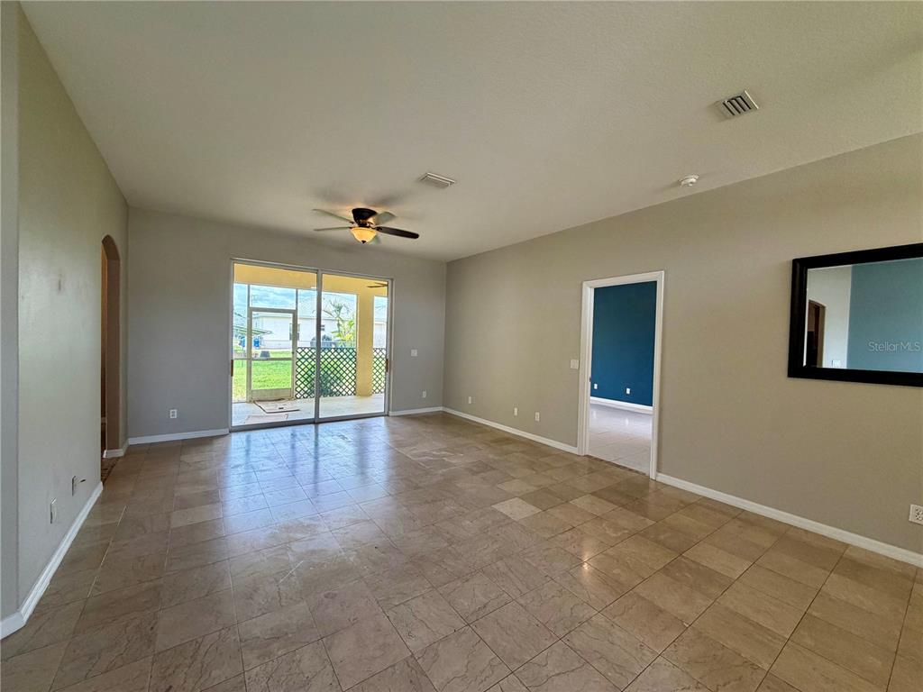 A living room with tile flooring, a ceiling fan, and sliding glass doors to a patio — 1204 S SAN MATEO DRIVE, NORTH PORT, FL
