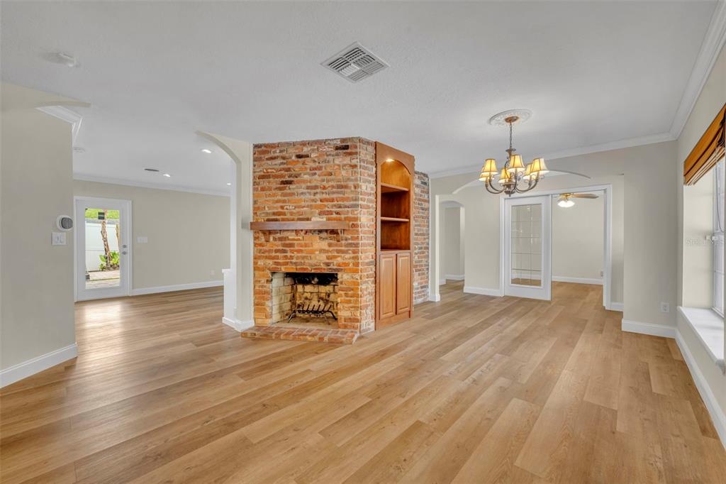 A living room with light wood floors, a brick fireplace, and built-in wooden shelving — 2112 CHIPPEWA TRAIL, MAITLAND, FL