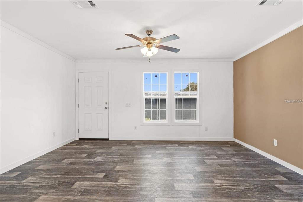An empty room with white walls, a tan accent wall, and wood-look flooring — 5234 YELLOW PINE STREET N, ST PETERSBURG, FL