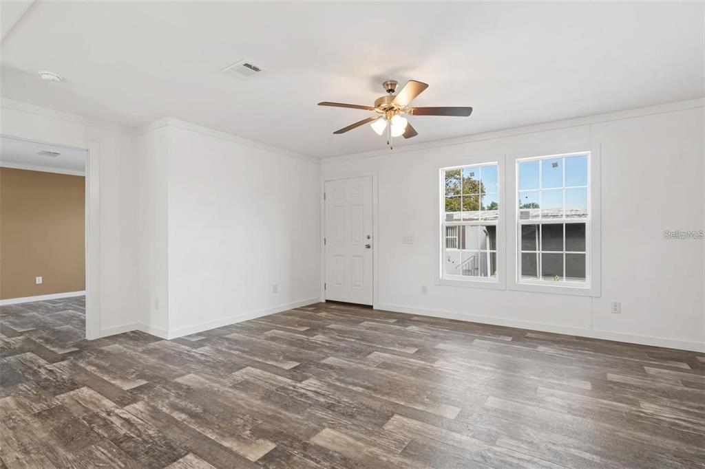 A bright room features white walls, wood-look flooring, a ceiling fan, and two windows — 5234 YELLOW PINE STREET N, ST PETERSBURG, FL