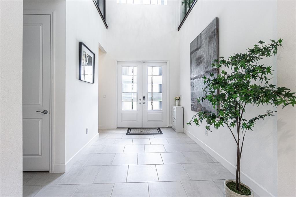 A bright entryway features white tile floors, a high ceiling, double front doors, and a plant — 32353 ROSEWOOD MEADOW LANE, WESLEY CHAPEL, FL
