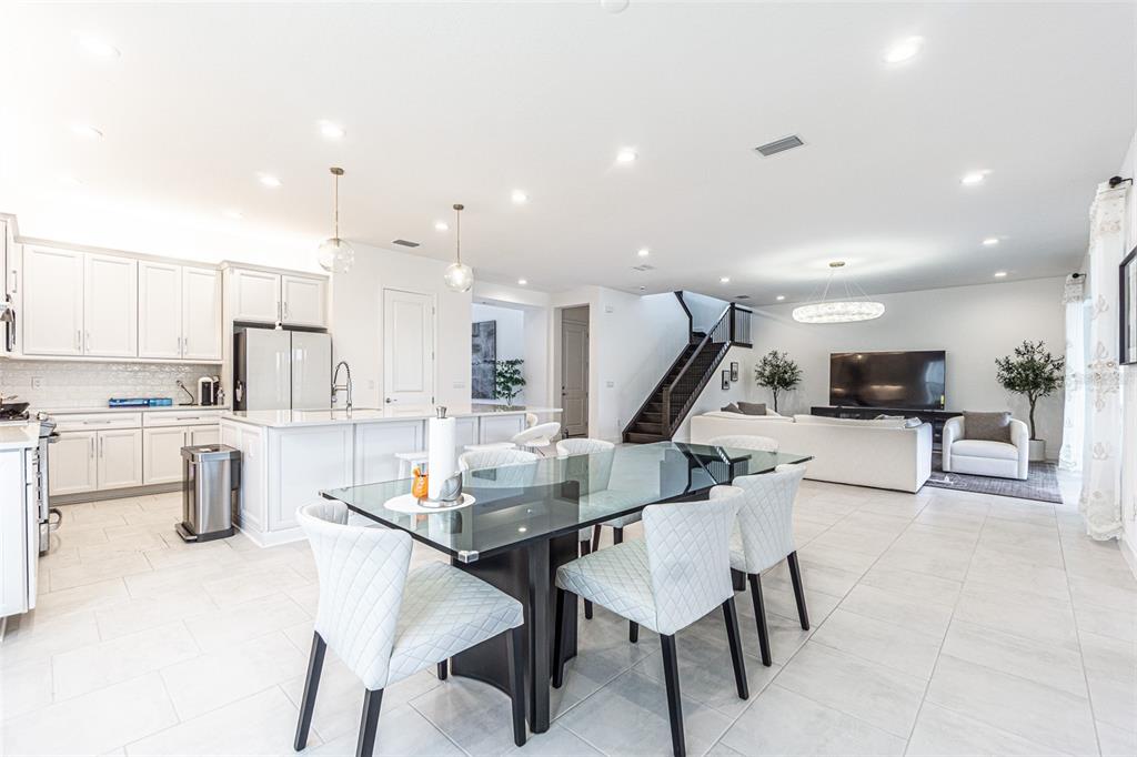 An open-concept kitchen, dining area, and living room feature white cabinetry and tile flooring — 32353 ROSEWOOD MEADOW LANE, WESLEY CHAPEL, FL