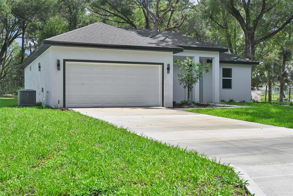 A single-story house with a white exterior, dark roof, and a two-car garage — 13855 SW 110TH PLACE, DUNNELLON, FL