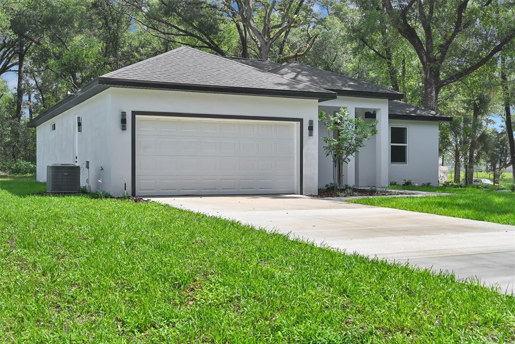 A white single-story house with a two-car garage and a concrete driveway — 13855 SW 110TH PLACE, DUNNELLON, FL