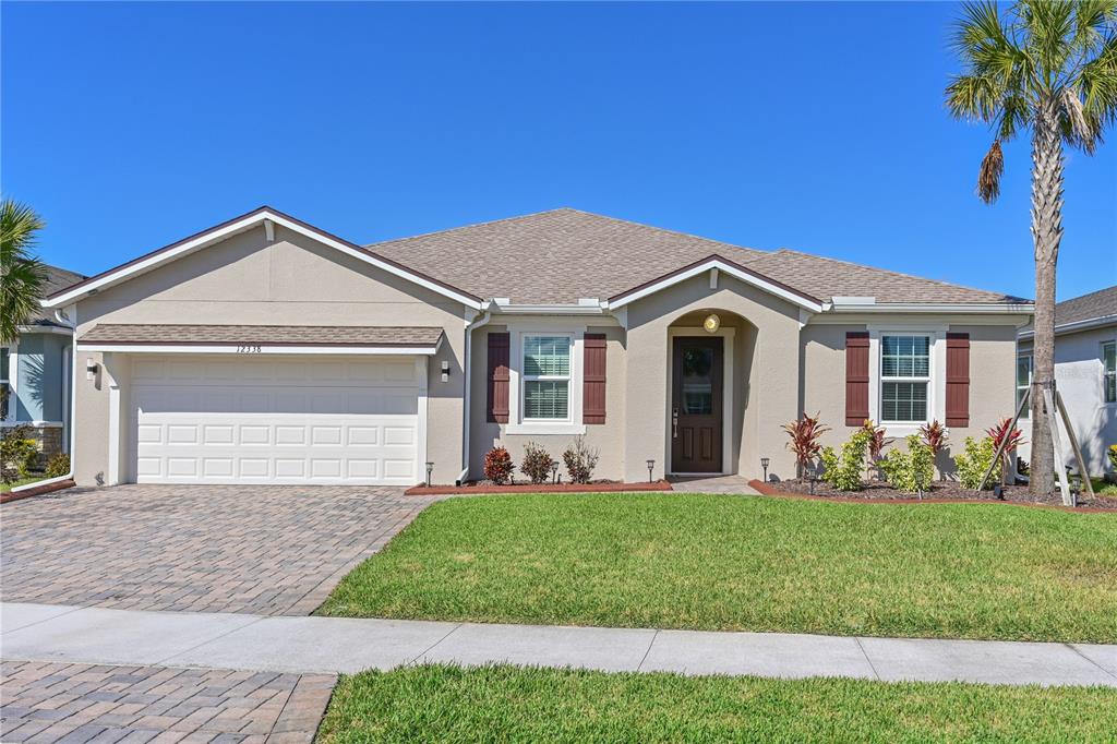 A single-story house with a beige stucco exterior, brown shutters, and a paved driveway — 12338 51ST STREET E, PARRISH, FL