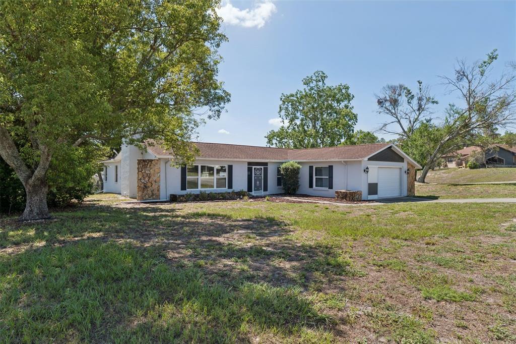 A single-story house with a stone accent wall, a garage, and a large front yard — 10200 SUNBURST COURT, SPRING HILL, FL