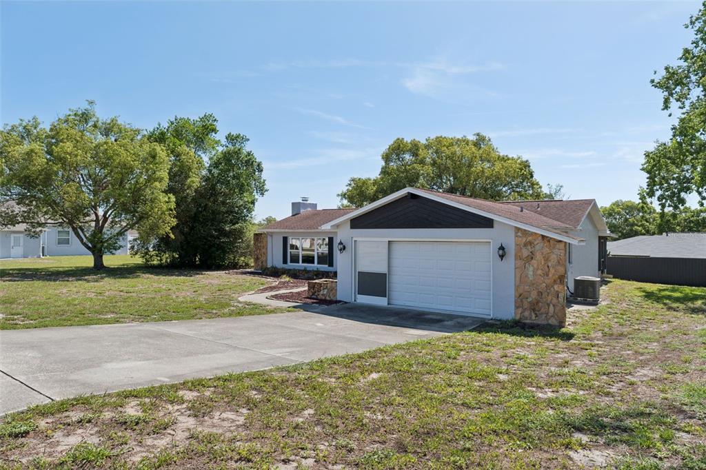 A single-story house exterior features a concrete walkway leading to a screened front door — 10200 SUNBURST COURT, SPRING HILL, FL