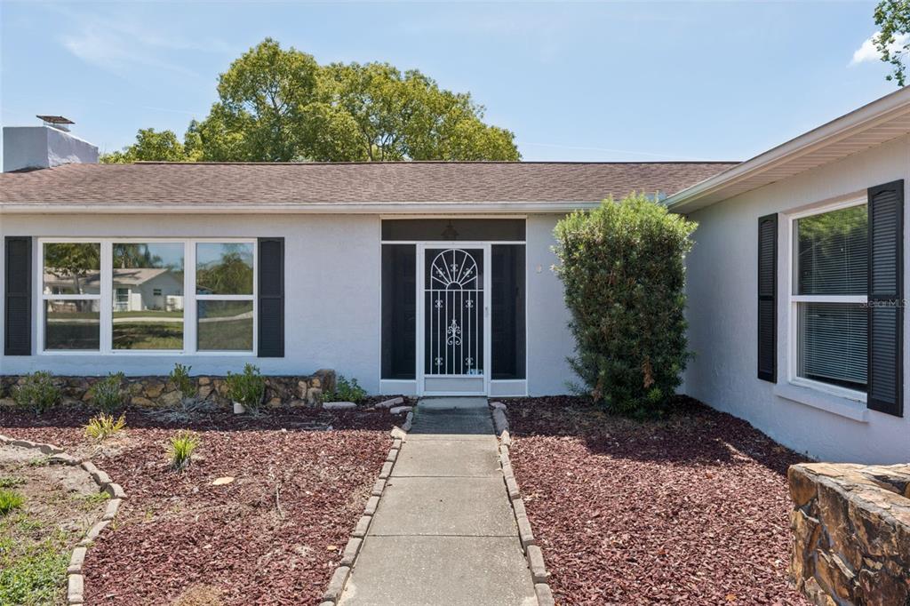 A hallway with tile flooring leads to a wooden double door and an adjacent room — 10200 SUNBURST COURT, SPRING HILL, FL
