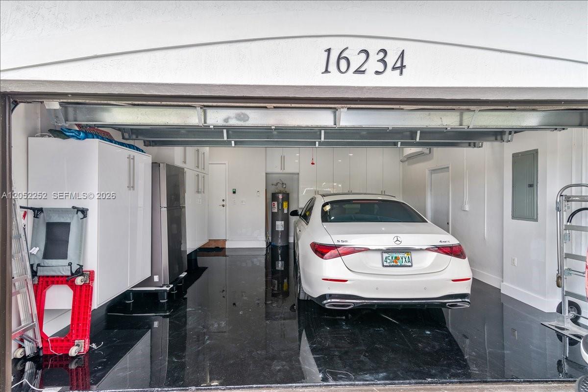A white sedan is parked inside a garage with white cabinets and a dark floor — 16234 SW 48th Ter, Miami FL 33185, MIAMI, FL