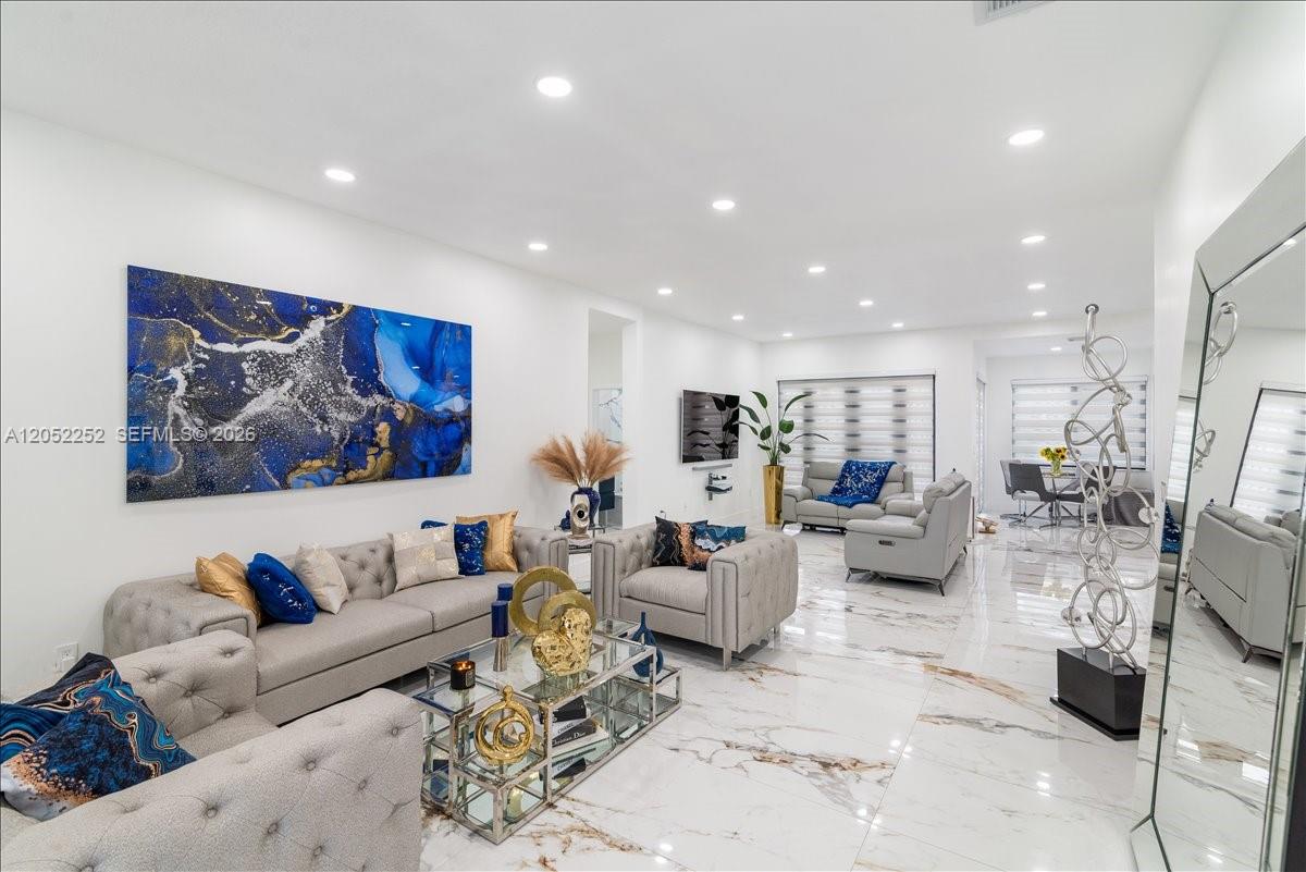 A bright living room features white marble floors, tufted grey furniture, and large blue artwork — 16234 SW 48th Ter, Miami FL 33185, MIAMI, FL