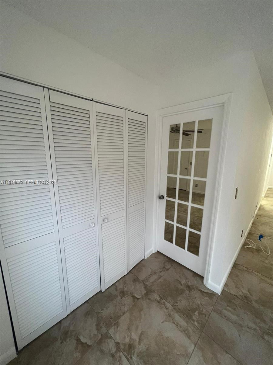 A white louvered closet sits next to a glass-paneled door on a tiled floor — 3460 N Pinewalk Dr N # 315, Margate FL 33063, MARGATE, FL