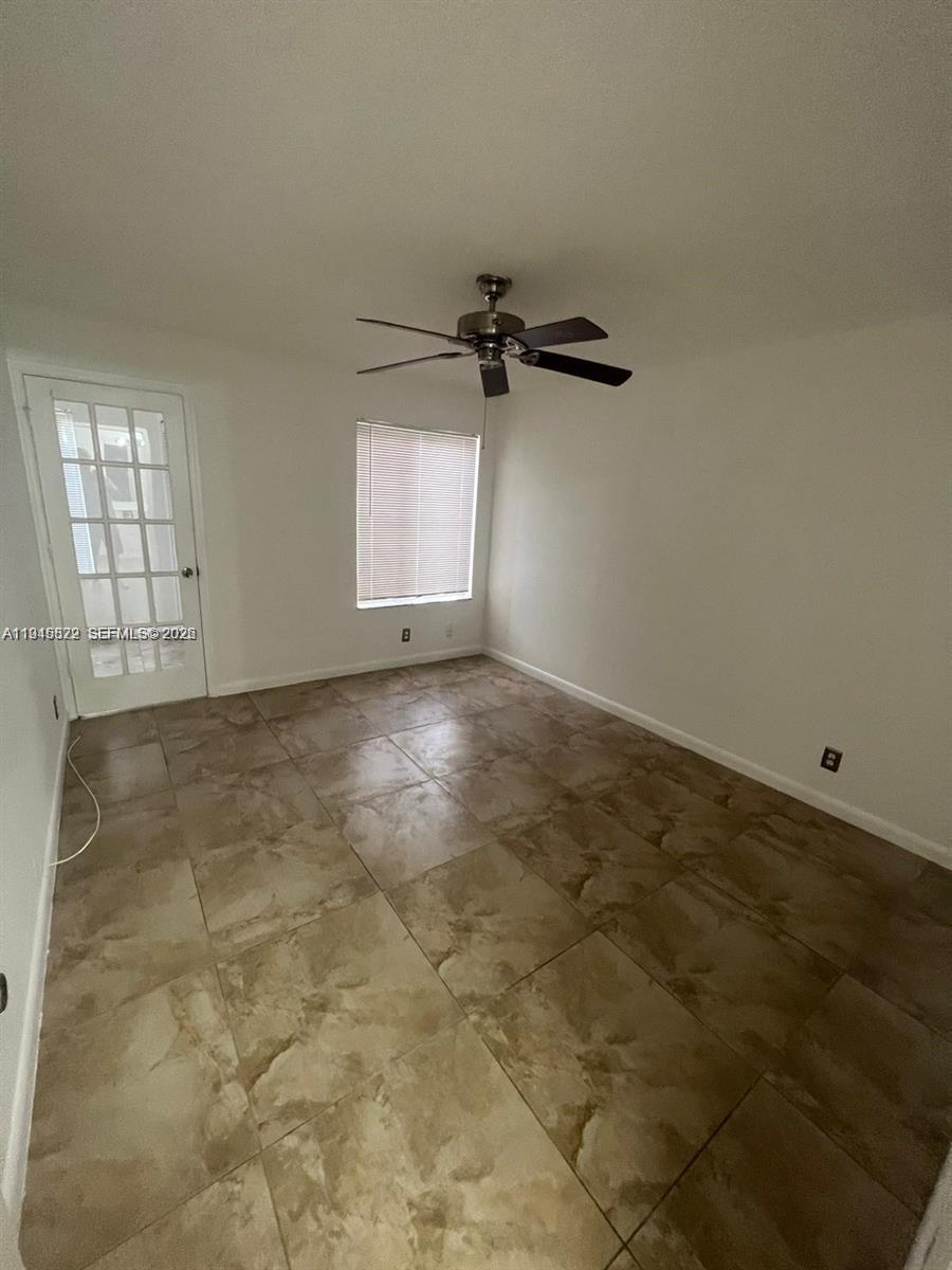 An empty room features tiled flooring, a ceiling fan, a window with blinds, and a door — 3460 N Pinewalk Dr N # 315, Margate FL 33063, MARGATE, FL