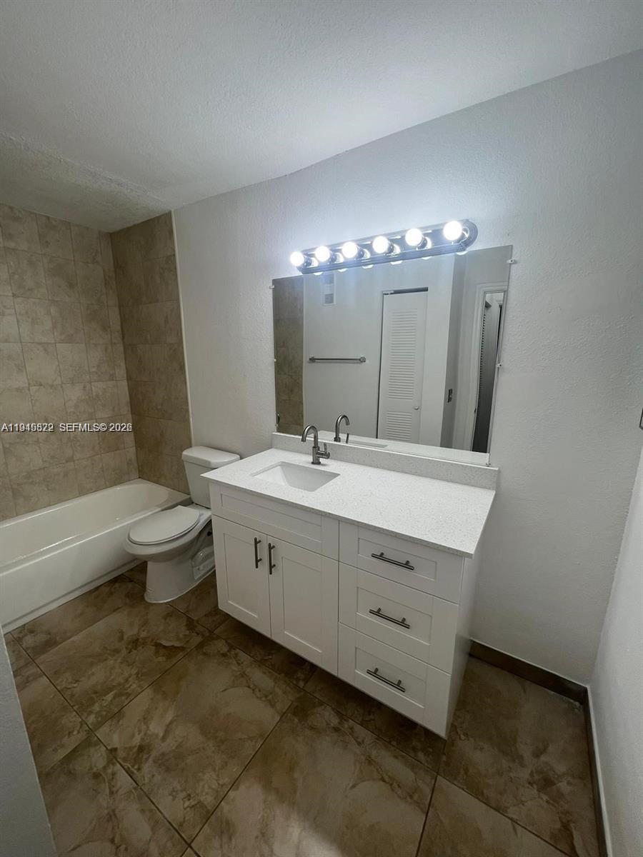 A bathroom features a white vanity, a mirror with a light fixture, and a bathtub — 3460 N Pinewalk Dr N # 315, Margate FL 33063, MARGATE, FL