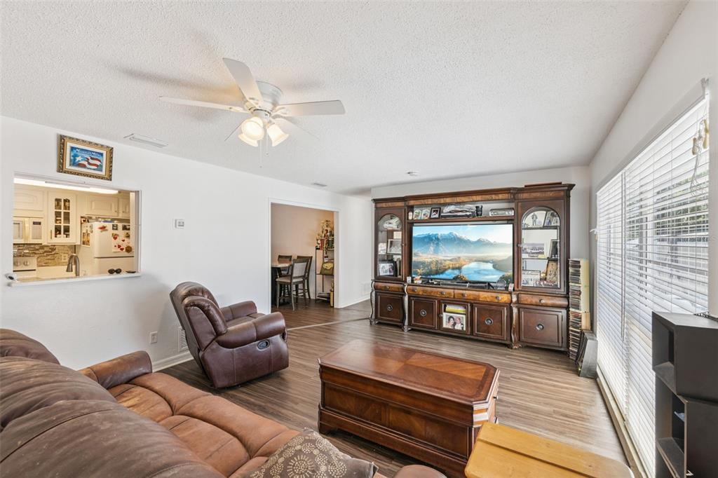 A living room with wood-look flooring, a large entertainment center, and a brown leather sofa — 1297 TIVOLI DRIVE, DELTONA, FL
