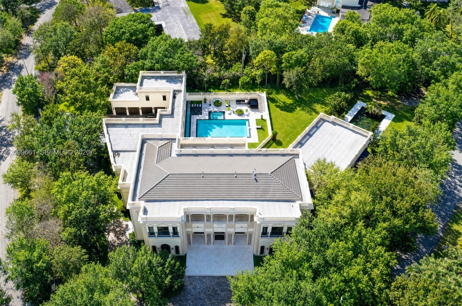 An aerial view shows a large multi-story mansion with a pool, patio, and surrounding trees — 5801 Moss Ranch Rd, Pinecrest FL 33156, PINECREST, FL