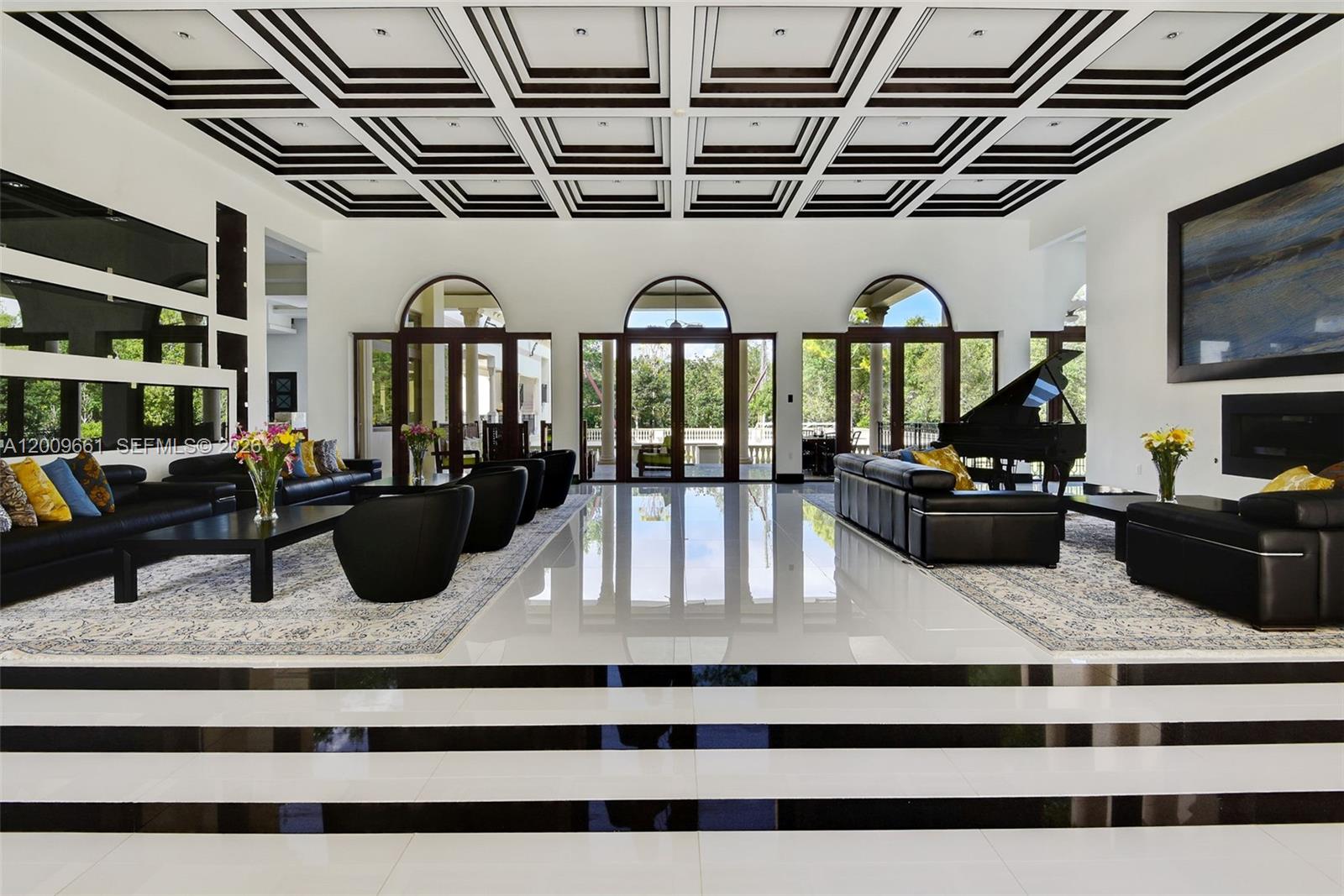 A spacious living room features a coffered ceiling, black and white flooring, and a grand piano — 5801 Moss Ranch Rd, Pinecrest FL 33156, PINECREST, FL
