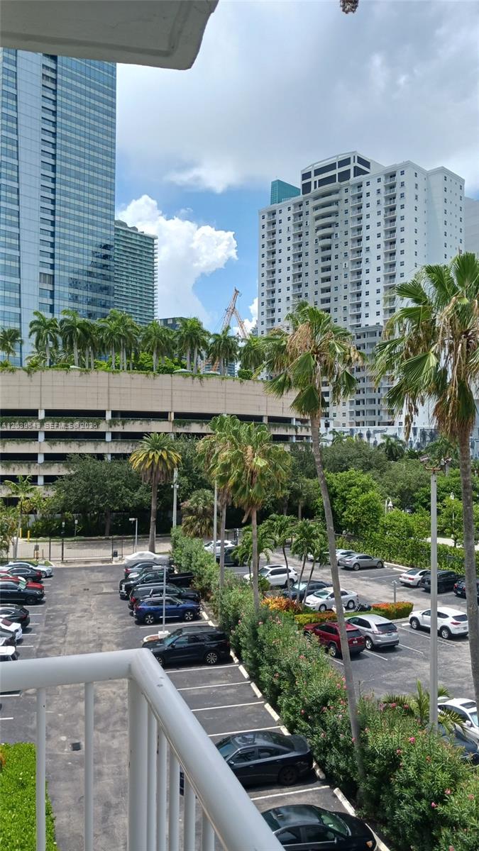 An elevated view shows a parking lot with many cars surrounded by palm trees and buildings — 1440 Brickell Bay Dr # 509, Miami FL 33131, MIAMI, FL