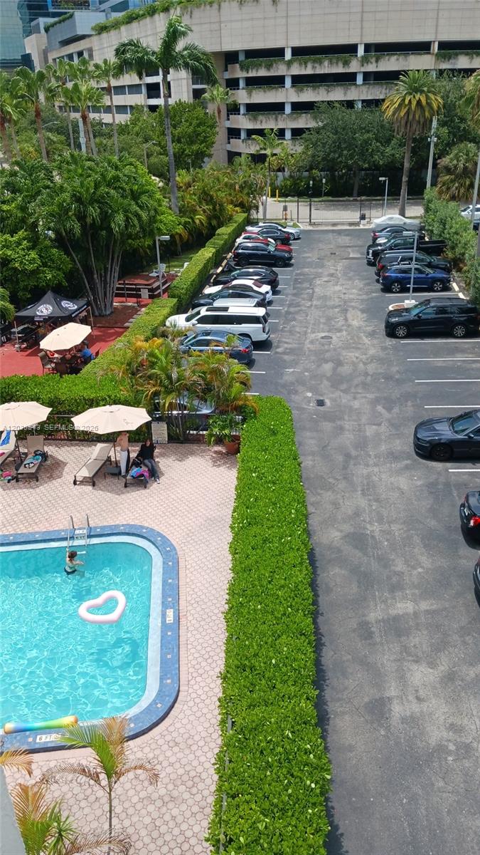 An elevated view shows a swimming pool with lounge chairs next to a parking lot — 1440 Brickell Bay Dr # 509, Miami FL 33131, MIAMI, FL