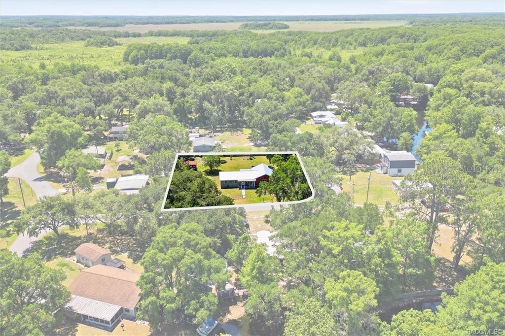 An aerial view shows a house with a red roof situated on a wooded lot — 5515 S BLUEGILL WAY, FLORAL CITY, FL