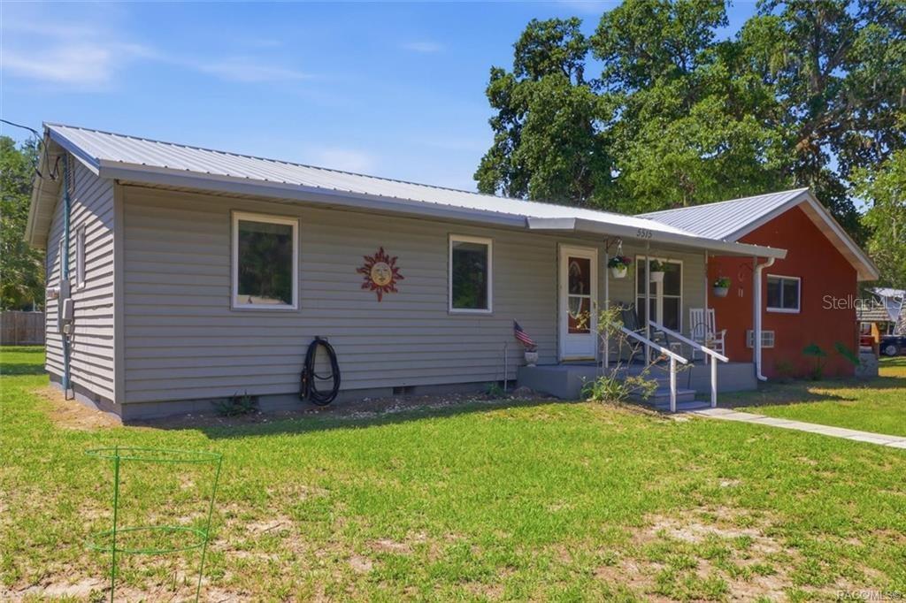 A single-story house with gray horizontal siding, a metal roof, and a small front porch — 5515 S BLUEGILL WAY, FLORAL CITY, FL