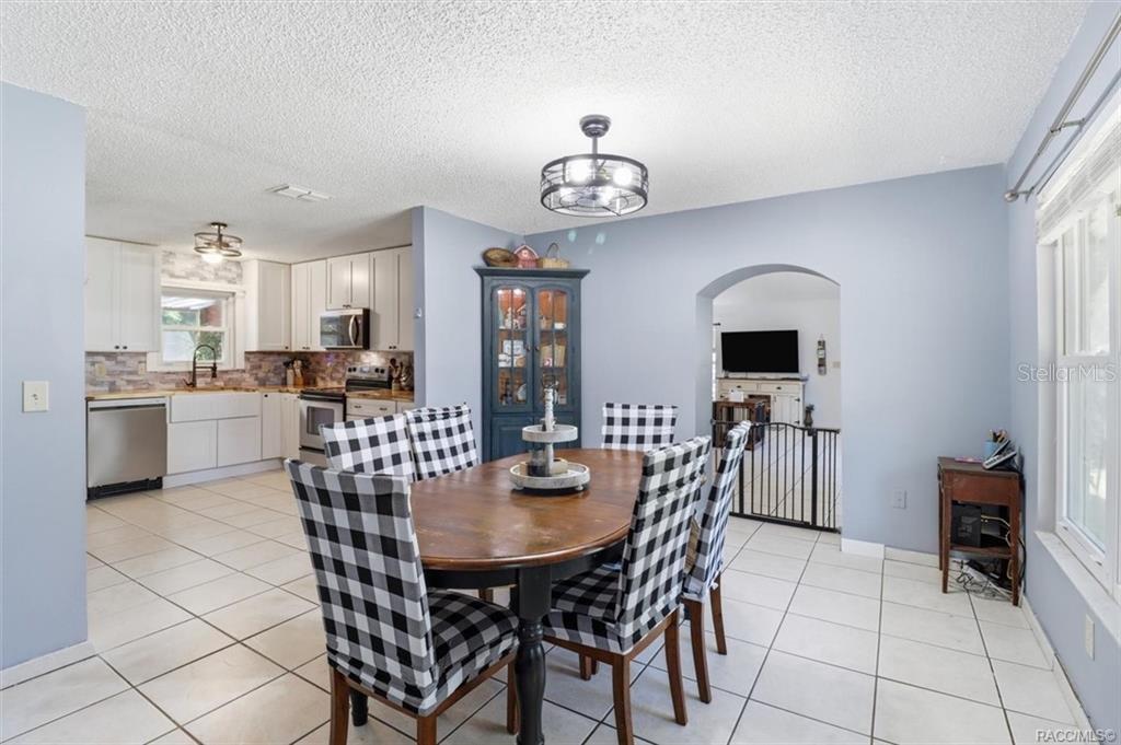 A dining area with a wooden table, buffalo check chairs, and an adjacent white kitchen — 5515 S BLUEGILL WAY, FLORAL CITY, FL