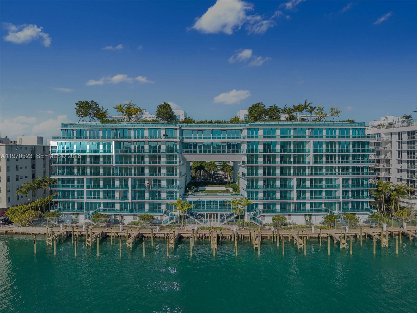 An exterior view of a multi-story waterfront apartment building with glass balconies and boat docks — 9201 E Bay Harbor Dr, Bay Harbor Islands FL 33154, BAY HARBOR ISLANDS, FL