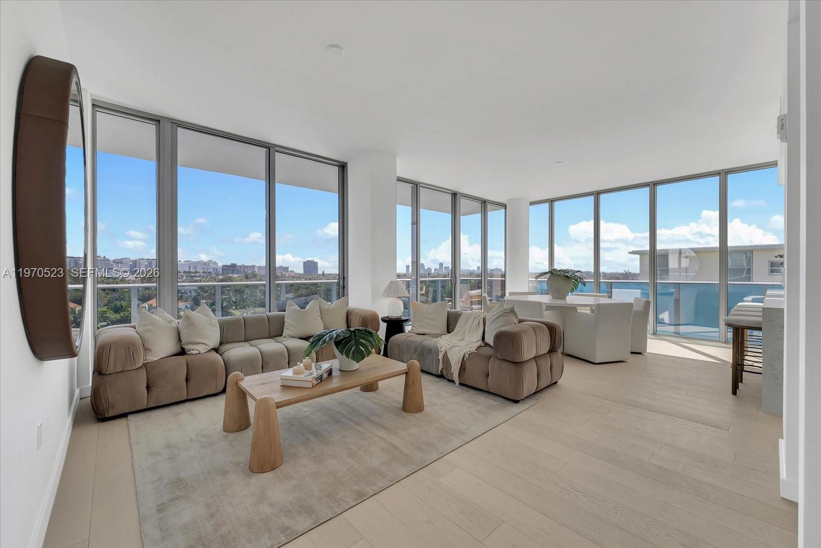 A modern living room features floor-to-ceiling windows, light wood flooring, and a large sectional sofa — 9201 E Bay Harbor Dr, Bay Harbor Islands FL 33154, BAY HARBOR ISLANDS, FL