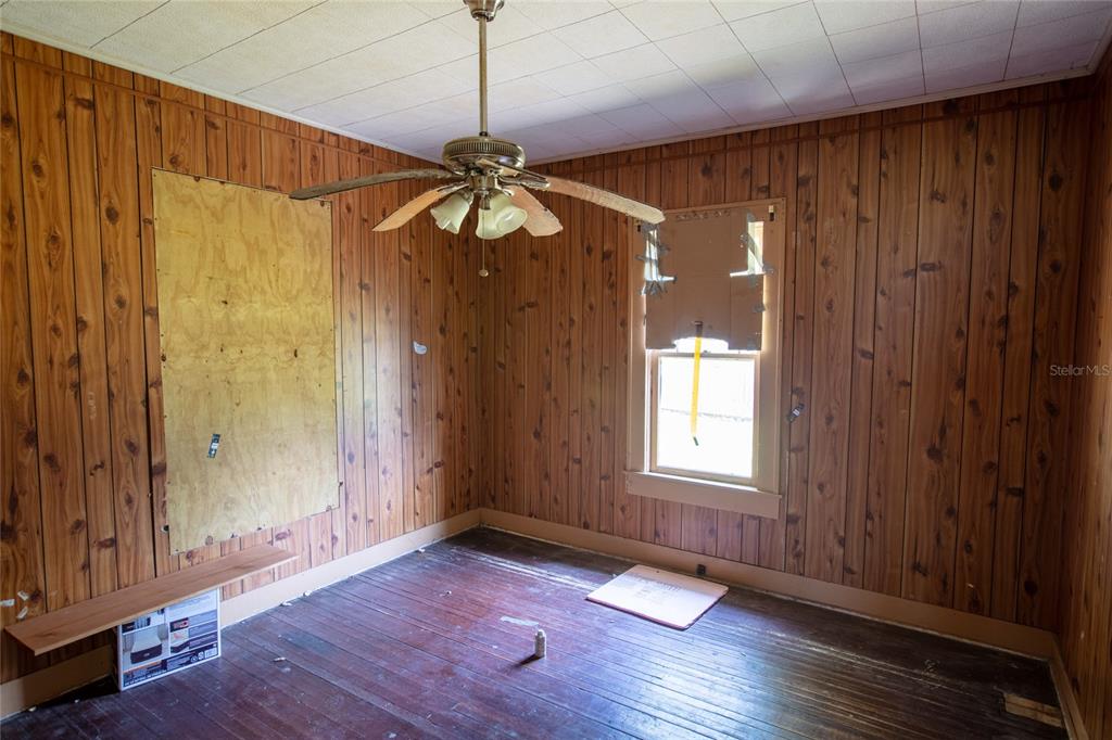 An empty room features wood-paneled walls, a ceiling fan, and dark hardwood flooring — 14962 NE US HIGHWAY 301, WALDO, FL