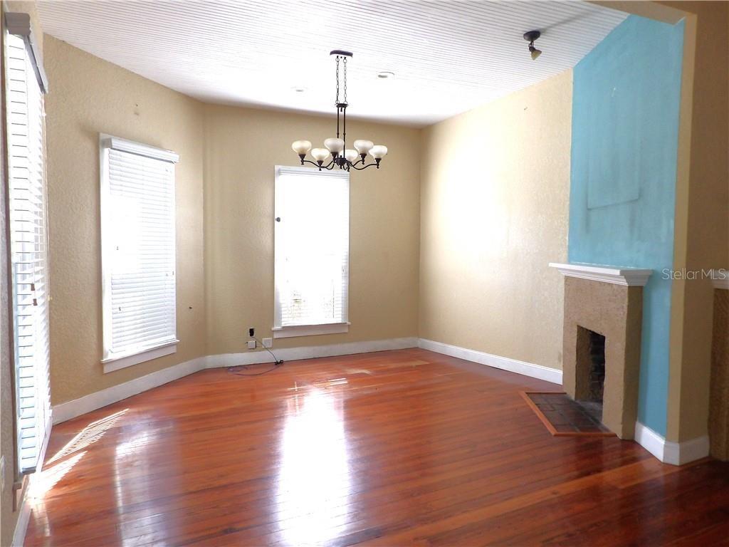 A dining room features hardwood floors, a fireplace, a chandelier, and light-colored walls — 401 TOMPKINS STREET, INVERNESS, FL